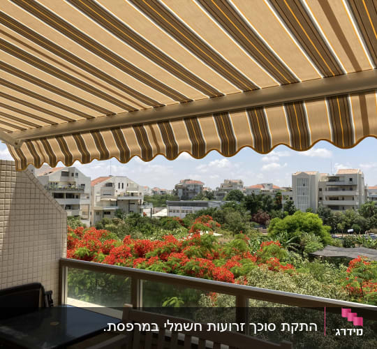 סוכך זרועות מתקפל עם בד פסים פרוס במרפסת דירה